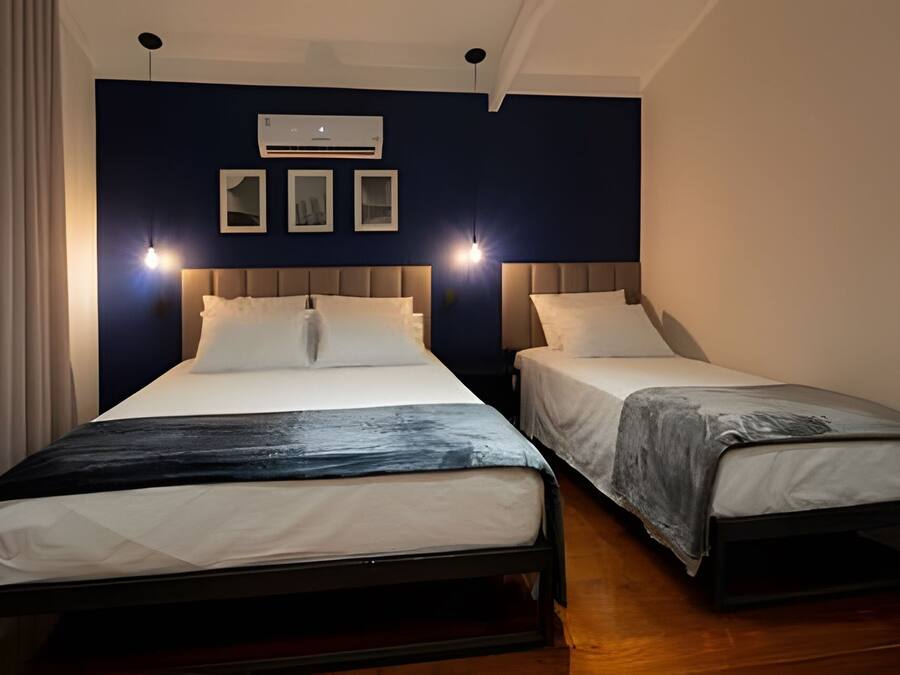 Una habitación de hotel con dos camas, ventilador de techo y aire acondicionado.