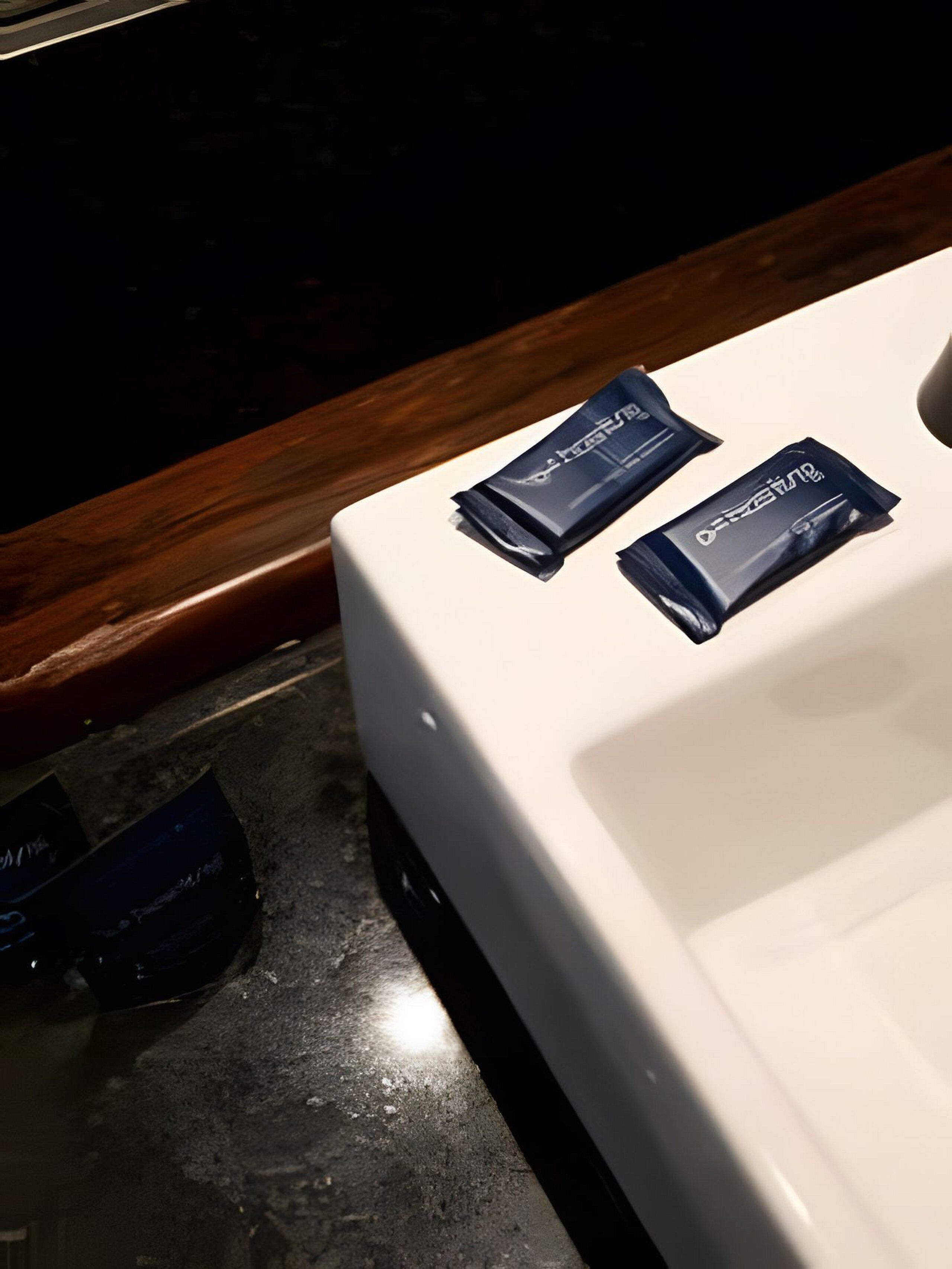 Una encimera de baño blanca con dos paquetes azul oscuro etiquetados "DUF" encima.