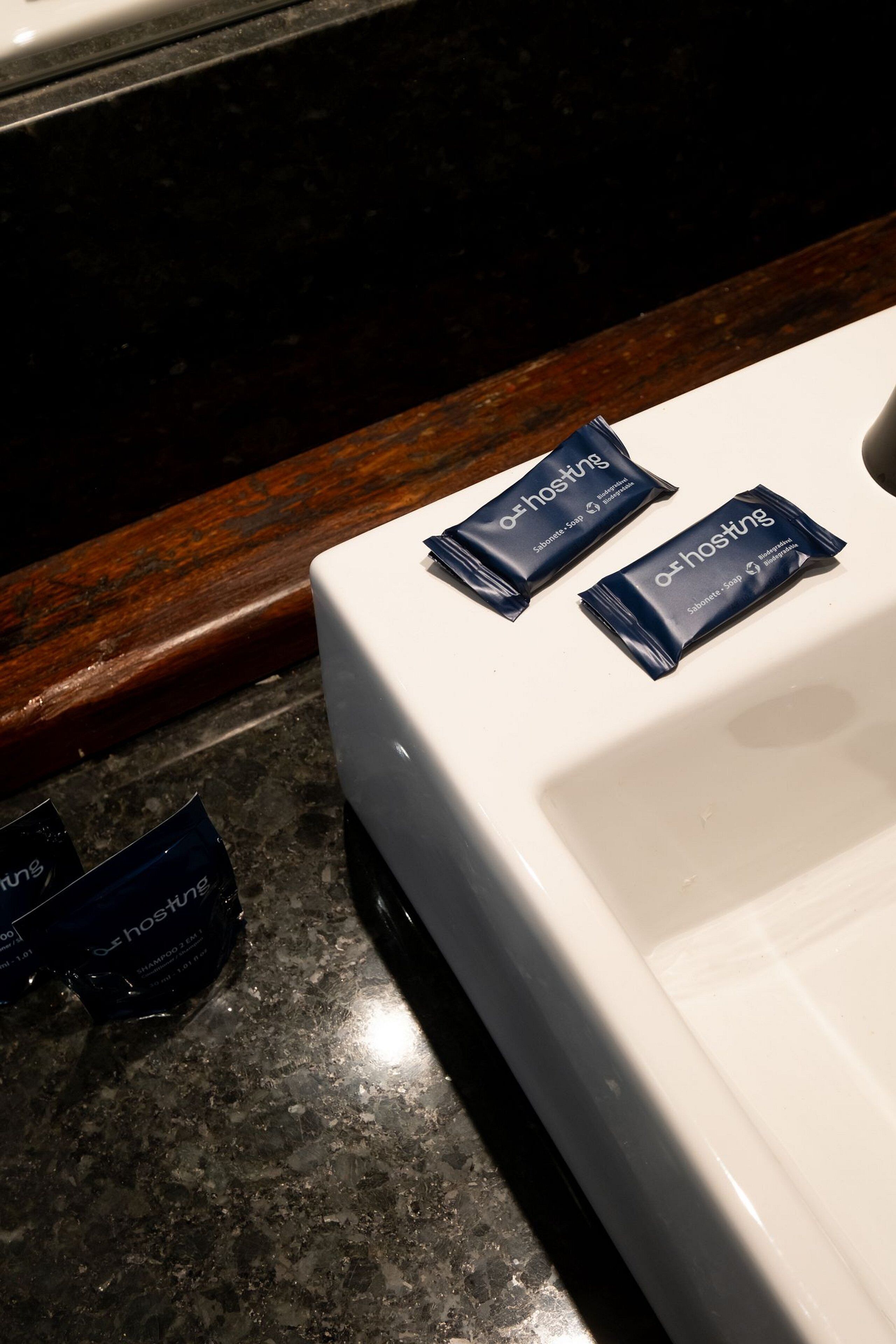 A white bathroom sink with two packets of soap placed on it.