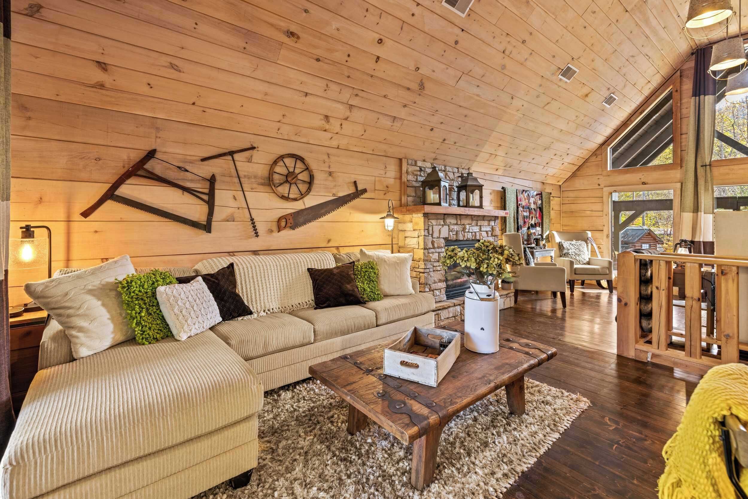 L’intérieur chaleureux d’un chalet avec un plafond en bois, un canapé, une table basse et une cheminée en pierre.