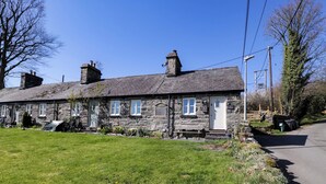 A stone building with a grassy front yard, a bench, and a picnic table.