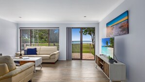 Una sala de estar moderna con un gran ventanal corredero que da a un balcón con vistas al mar.