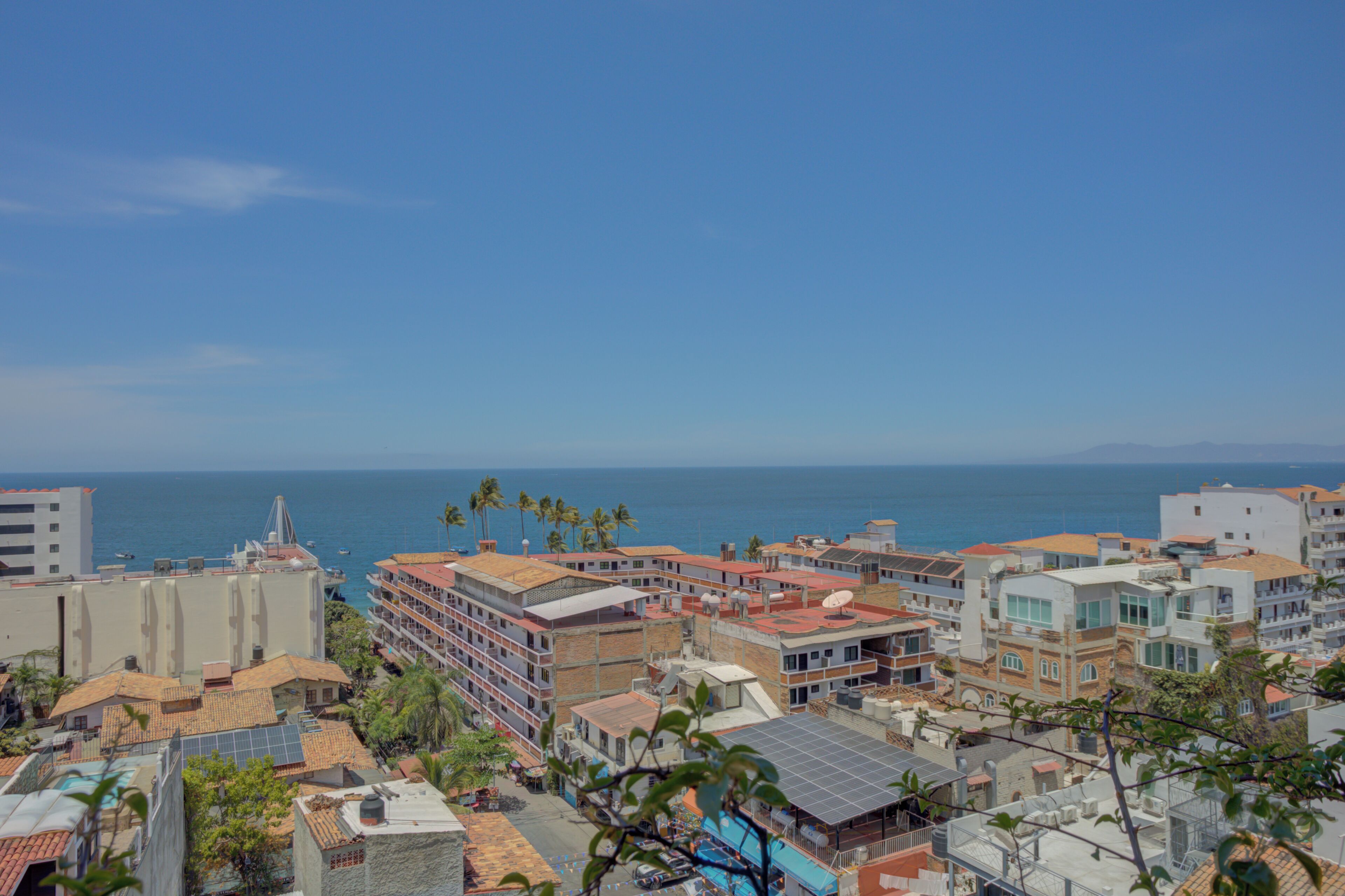 Una zona urbana costera con edificios, algunos con paneles solares, y vista al mar.
