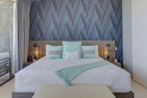 Een hotelkamer met een groot bed, een hoofdeinde met geometrische patronen, nachtlampjes en uitzicht op de omgeving.