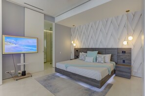 Une chambre moderne dotée d’un grand lit, d’une télévision et d’un décor mural géométrique original.