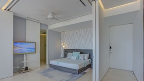 A modern bedroom with a bed, a television, and a ceiling fan. - Pier 57 Luxury | Ocean Views, Infinity Pool & Bar (Puerto Vallarta)
