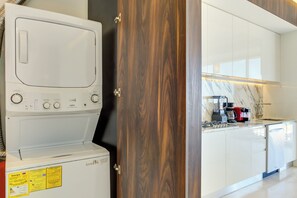 A modern kitchen with white appliances, a wooden door, and a marble backsplash.
