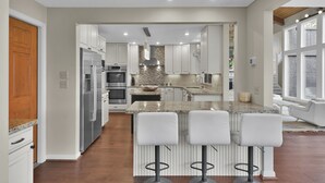 A modern kitchen with white cabinets, stainless steel appliances, and a central island with bar stools.