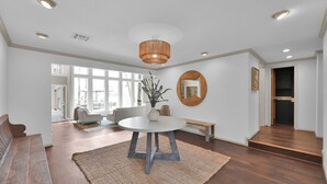 A spacious living room with a round table, a large mirror, and a staircase leading to another level.