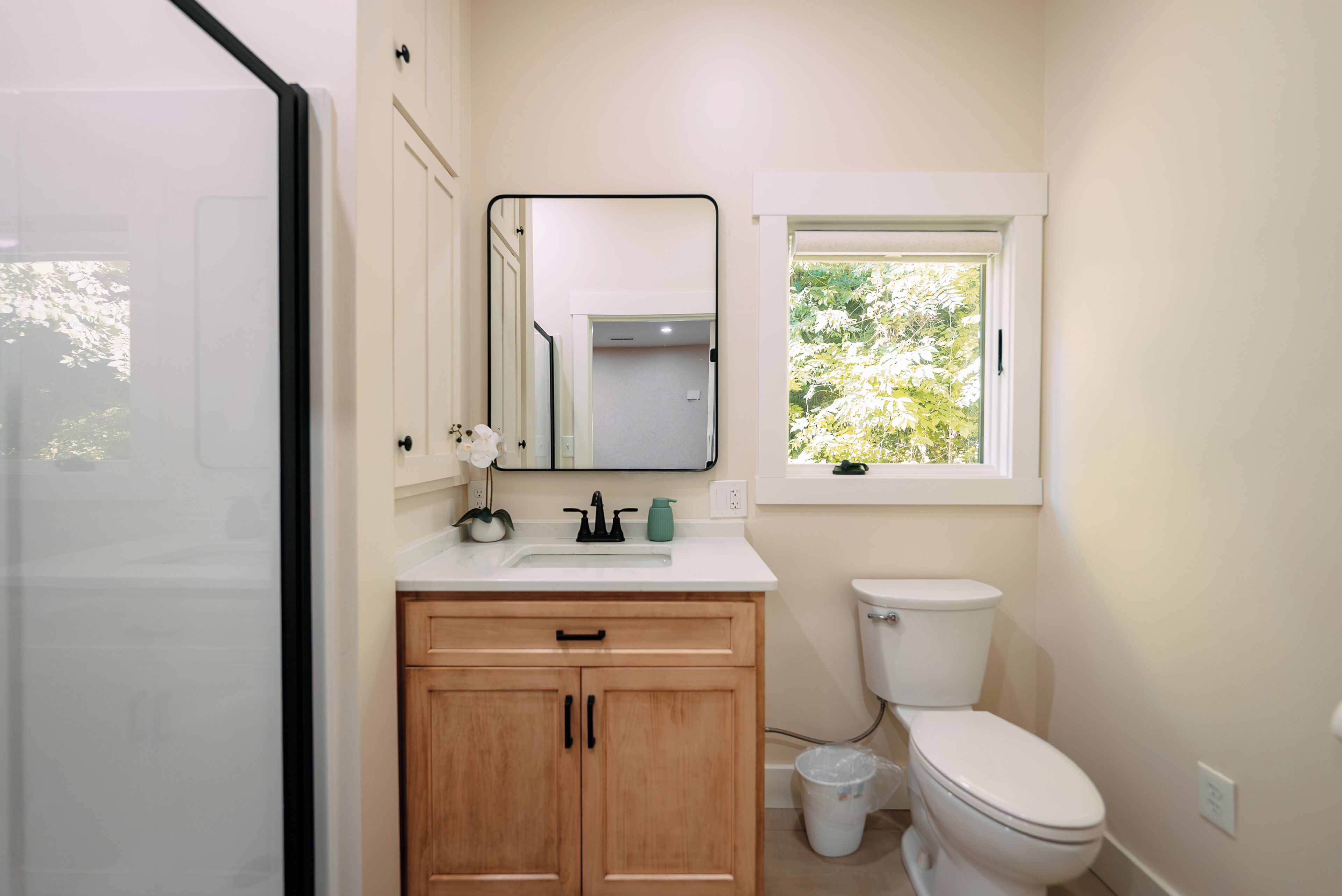 Un bagno con il water, lavandino, specchio e finestra.