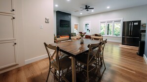 Une cuisine moderne avec une table à manger, des chaises, un ventilateur de plafond et un four encastré.