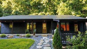 Un bâtiment à deux étages, avec un chemin de pierre menant à l'entrée, entouré de verdure.
