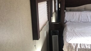 A bedroom with a bed, a mirror, a heater, and a window with blinds. - Cozy caravan with WiFi and AC in charming Thermal.Private location (Thermal)