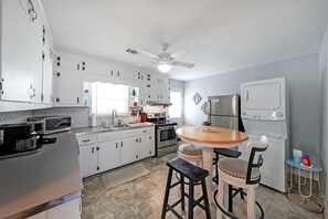 Una cocina moderna con armarios blancos, una isla central, un ventilador de techo y un horno empotrado.