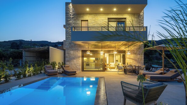 A modern two-story house with a swimming pool, outdoor seating, and a well-lit patio area. - Feli Living - luxury villa Chania Crete Greece (Spilia)
