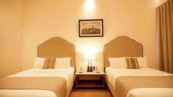 A hotel room with two beds, a nightstand with a lamp, and a framed picture on the wall.