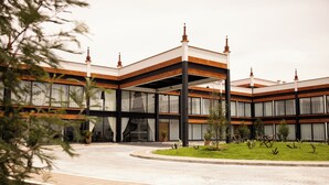 A modern building with a curved driveway, large windows, and a well-maintained lawn with potted plants. - Hotel La Finca por Zotoluca (Apan)