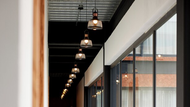 A corridor with a tiled floor, large windows, and hanging pendant lights. - Hotel La Finca por Zotoluca (Apan)