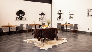 A modern art gallery with black and white paintings on the walls, a central table with a fruit basket, and a rustic rug on the floor. - Hotel La Finca por Zotoluca (Apan)