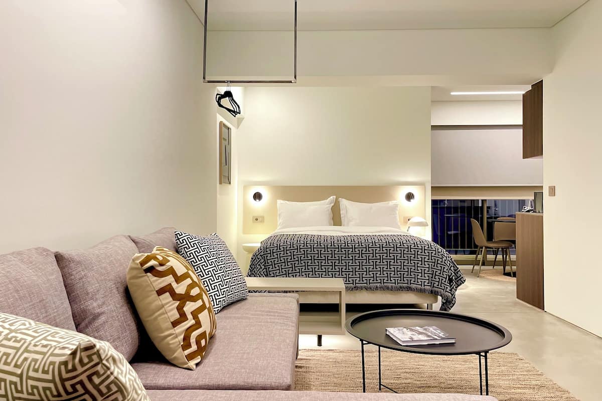 Ein modernes Hotelzimmer mit Bett, Sofa und einem kleinen runden Tisch.