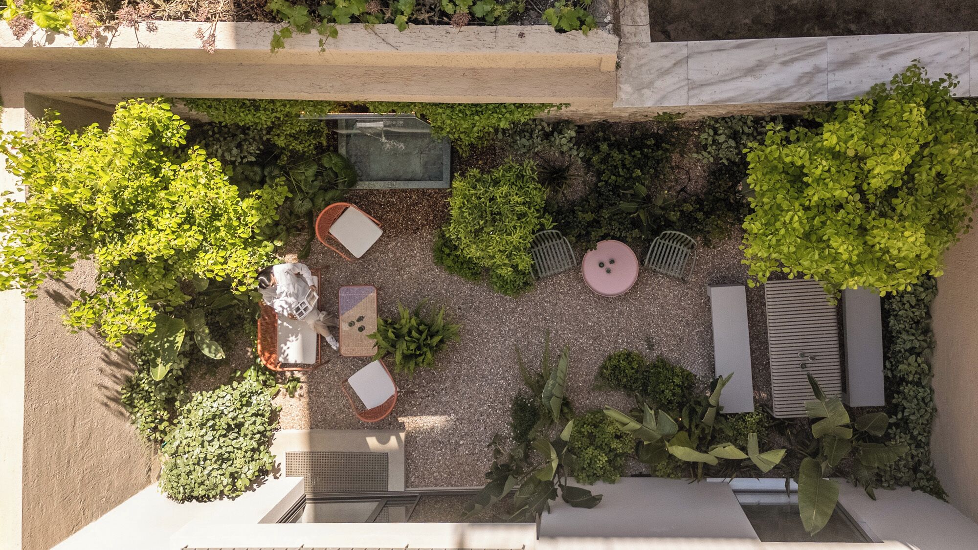 Jardim no terraço com área de estar externa, um elemento aquático e diversas plantas.