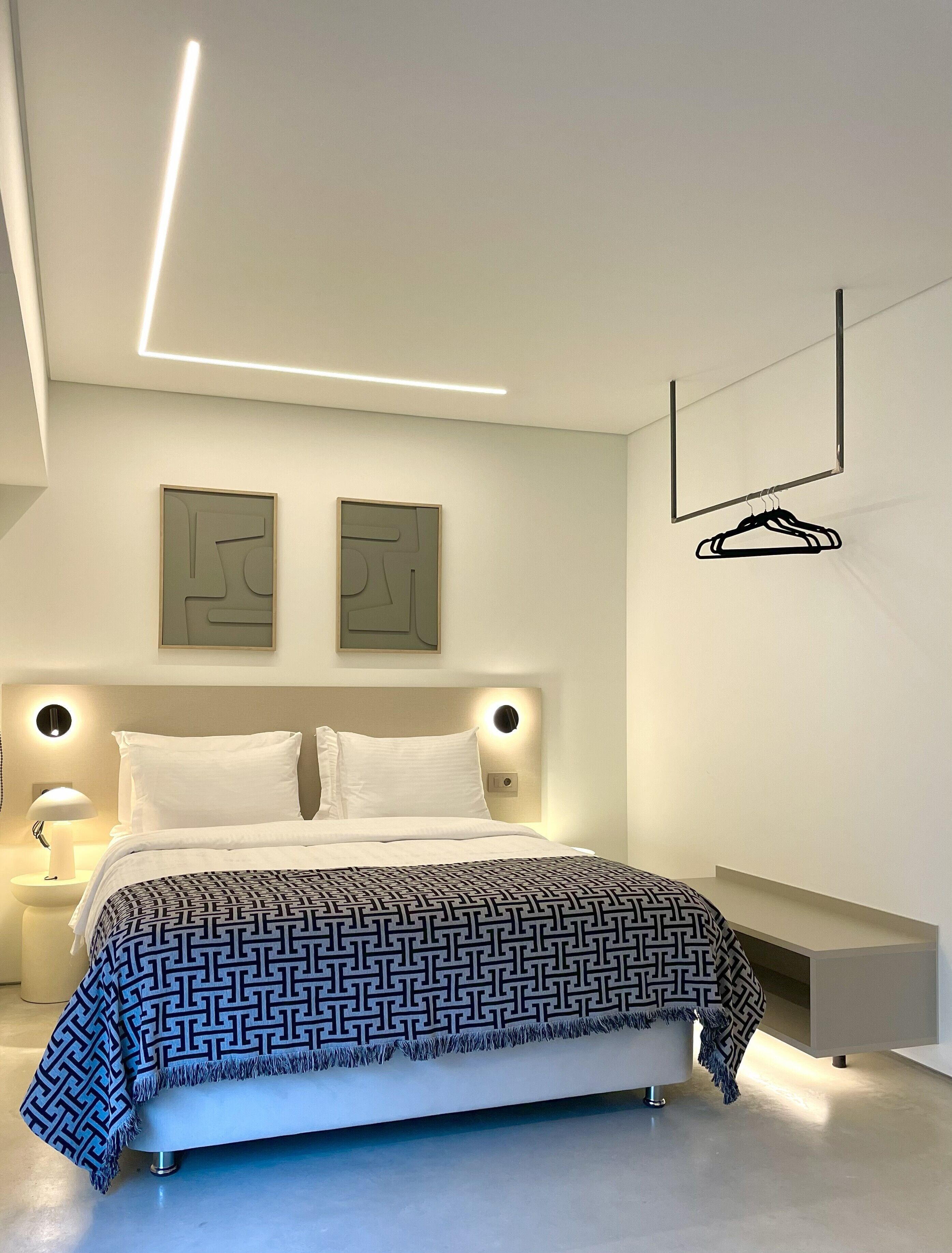 Ein modernes Schlafzimmer mit Bett, Nachttischen, einer Wandleuchte und abstrakter Wandkunst.