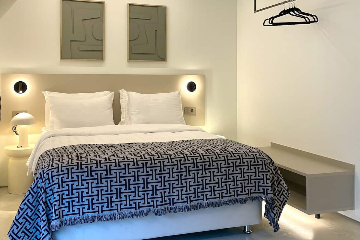 Ein modernes Schlafzimmer mit Bett, Nachttischen, einer Wandleuchte und abstrakter Wandkunst.