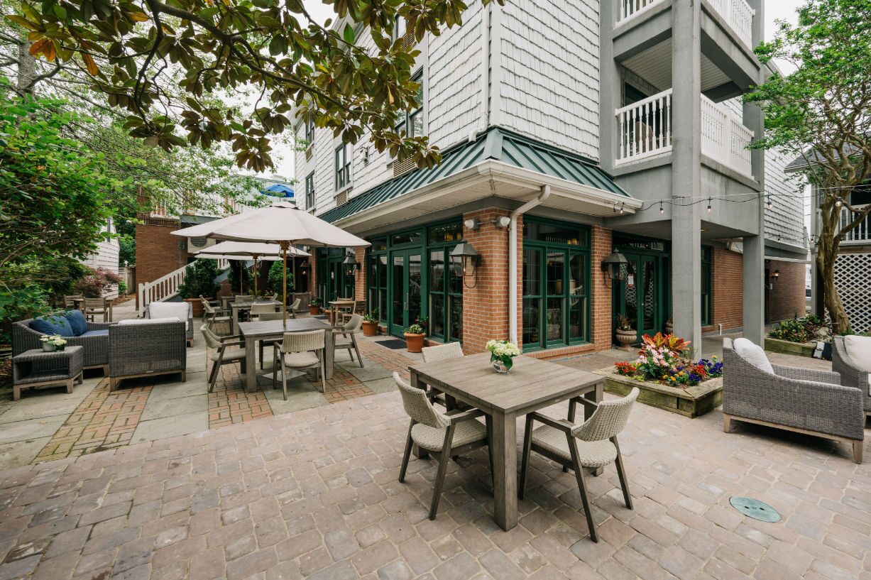An outdoor patio area with a dining table, chairs, and a covered seating area.