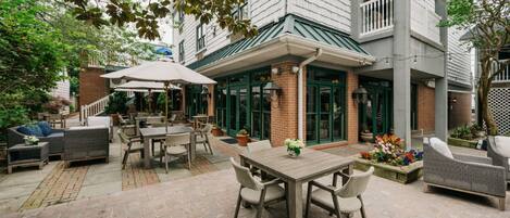 An outdoor patio area with a dining table, chairs, and a covered seating area.