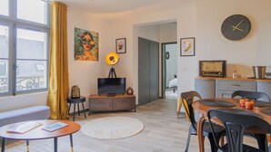 Ein modernes Wohnzimmer mit Fernseher, Essbereich und Kunstwerken an den Wänden.