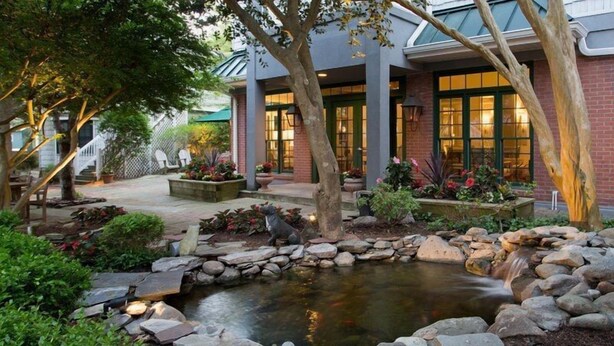 A landscaped garden with a pond, stone borders, and a statue. - Scenic King Room | Garden Views & Easy Access (Rehoboth Beach)
