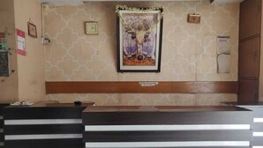 A reception area with a reception desk, a wall clock, and a framed artwork above the desk. - Deteex Classic Inn (Barakpur)