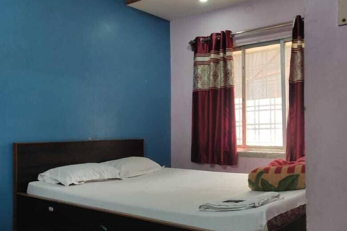 A bedroom with a bed, a ceiling fan, a window with curtains, and a tiled floor.