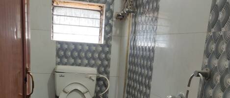 A small bathroom with a toilet, a sink, a shower, and a window.