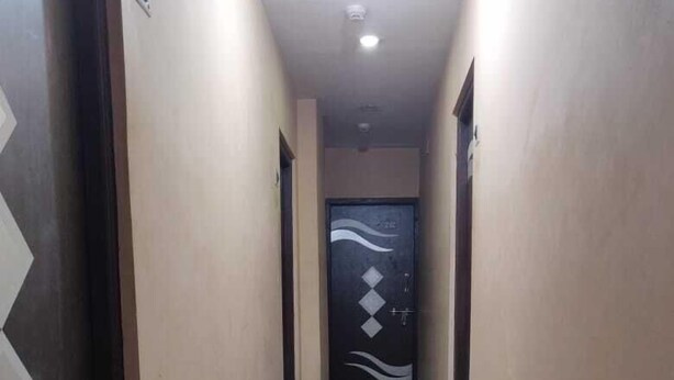 A hallway with a marble floor, beige walls, and a door with a diamond pattern. - Deteex Classic Inn (Barakpur)