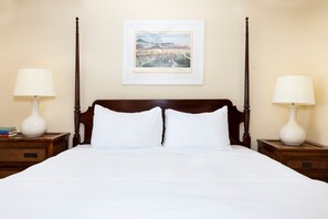 A neatly made bed with white linens, two bedside tables with lamps, and a framed picture on the wall. - Palmer House King | Vaulted Ceilings & Deck (Rehoboth Beach)