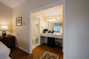 A bathroom with a toilet, sink, and shower. There is a mirror above the sink and a ceiling fan above the shower.