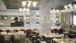 Un interior de restaurante con columnas de mármol, mesas de madera e iluminación moderna.