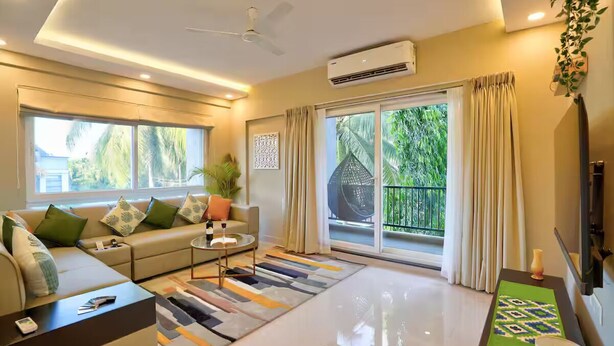 A modern living room with a sofa, coffee table, and a large window with curtains.