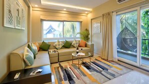 A modern living room with a sofa, coffee table, and a view of a house through large windows.