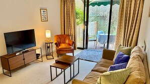 Een woonkamer met een televisie, een leren fauteuil, een bank en een bijzettafeltje.