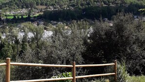 Un camino pavimentado con valla de madera que lleva a una vista panorámica de un pueblo y colinas.