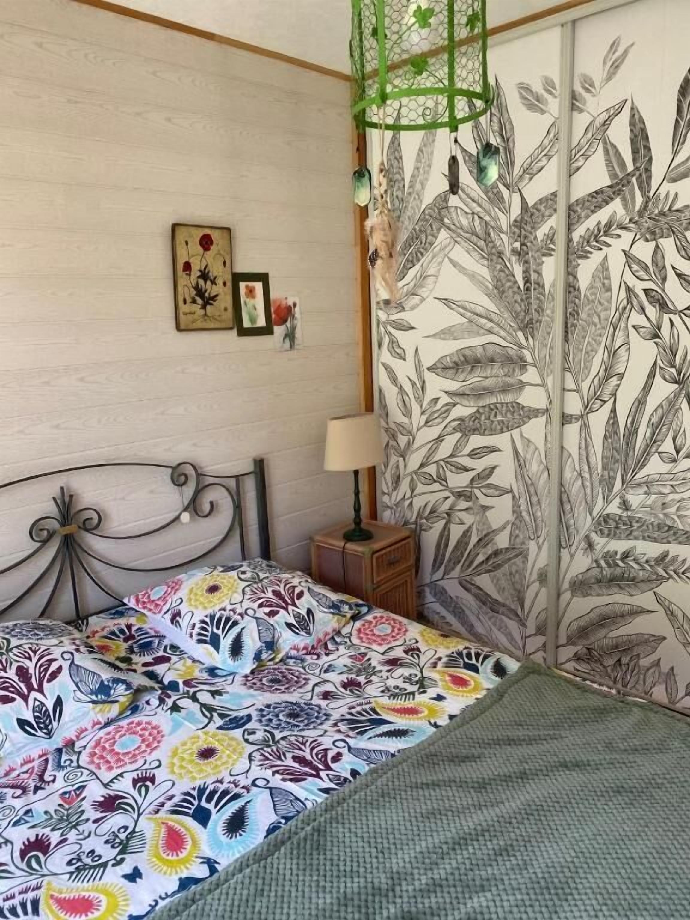 A bedroom with a bed, a nightstand, a lamp, and a wall with a botanical print.