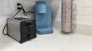 Une cuisine équipée d’un grille-pain Hamilton Beach, d’une machine à café Keurig et d’un porte-tasses décoratif.