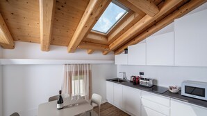 A modern kitchen with white cabinets, a wooden ceiling, and a skylight. - BORGO PAOLIN - Rooms in the Vineyard. A journey between culture and relaxation in the countryside. (Veneto)