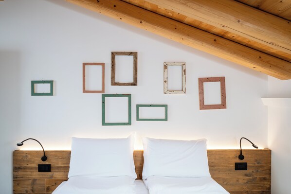 Ein Schlafzimmer mit einem hölzernen Kopfteil, zwei Nachttischen und einer Wand mit mehreren gerahmten Bildern.