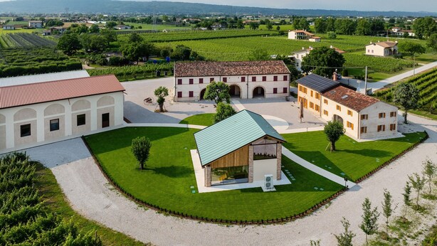 A large estate with multiple buildings, including a central courtyard with a modern structure, surrounded by lush green fields and vineyards. - BORGO PAOLIN - Rooms in the Vineyard. A journey between culture and relaxation in the countryside. (Veneto)