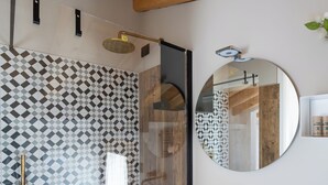 A modern bathroom with a geometric patterned shower wall, a round mirror, and a white sink with gold fixtures. - BORGO PAOLIN - Rooms in the Vineyard. A journey between culture and relaxation in the countryside. (Veneto)