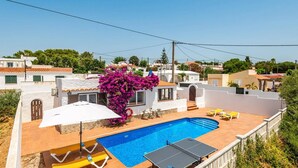 A residential property with a swimming pool, outdoor seating, and a view of neighboring houses.