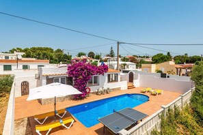 A residential property with a swimming pool, outdoor seating, and a view of neighboring houses.
